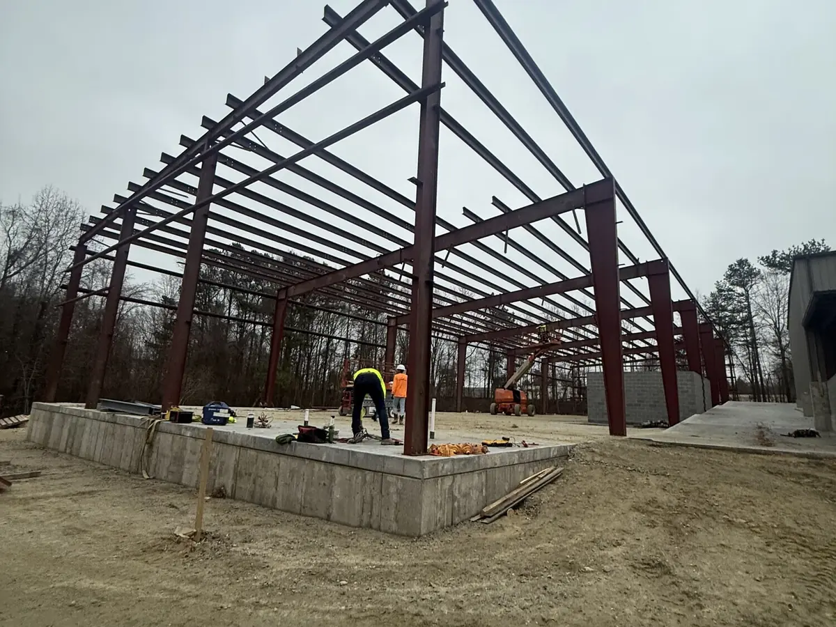 A red steel portal frame standing on new concrete foundations, ready for cladding